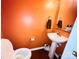 Half bathroom features a toilet, small sink, and an orange accent wall at 4048 Cascade Dr, Gastonia, NC 28056