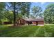 Beautifully landscaped backyard featuring a brick home, stamped concrete patio, gazebo, and mature trees at 4323 Crow Rd, Monroe, NC 28112