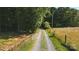 Gravel driveway leading to property through a wooded area with an adjacent open field at 4323 Crow Rd, Monroe, NC 28112