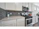 Close up of the kitchen featuring a gas range, stainless steel microwave, and gray backsplash at 440 Shallowford Dr, Rock Hill, SC 29732