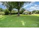 Large backyard featuring mature trees, a swing, and well-maintained lawn and landscaping at 5701 Cedar Hill Dr, Monroe, NC 28110