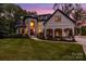 Elegant front exterior of a brick home with a stone turret, arched entry, and beautifully landscaped yard at 6327 Fox Tail Ln, Davidson, NC 28036