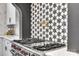 Close up of kitchen gas range, custom backsplash, and pot filler at 6327 Fox Tail Ln, Davidson, NC 28036