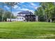 Elegant rear exterior of a white brick home with a spacious covered deck and a manicured lawn at 6327 Fox Tail Ln, Davidson, NC 28036