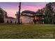 Elegant rear exterior of a brick home with a covered deck, mature trees, and sprawling lawn at 6327 Fox Tail Ln, Davidson, NC 28036