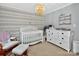Bedroom featuring a white crib, dresser, and soft gray walls with patterned accent wall at 8300 Quarters Ln, Mint Hill, NC 28227