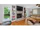 Cozy living room featuring a brick fireplace, built-in shelves, and hardwood flooring at 8300 Quarters Ln, Mint Hill, NC 28227