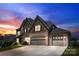 Stunning two-story home with a stone and brick exterior, twilight, and a long driveway to the garages at 837 Kathy Dianne Dr, Indian Land, SC 29707