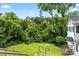Fenced in backyard with overgrown foliage and wood steps leading to the yard at 904 Edgewood Cir, Gastonia, NC 28052