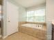 Bright bathroom features a soaking tub with tile surround and large window at 9212 John Hawks Rd, Cornelius, NC 28031
