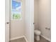 Compact powder room with tile flooring and a window, featuring essential fixtures in a neutral palette at 9221 Widden Way, Charlotte, NC 28269