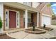 Welcoming brick front porch with a red door, white columns, and meticulously manicured landscaping beds and a seating area at 9429 Coast Laurel Nw Ave, Concord, NC 28027
