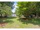 This backyard features a lush green yard, a swing, a privacy fence, and mature trees at 10600 Four Mile Creek Rd, Charlotte, NC 28277