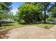 A backyard is seen featuring a brick paved patio and a large yard surrounded by trees and fencing at 10600 Four Mile Creek Rd, Charlotte, NC 28277