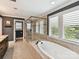 Bright primary bathroom features soaking tub under window, glass enclosed shower, and neutral tile at 1118 Yale Pl, Charlotte, NC 28209