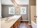 Bright bathroom featuring double sinks, wood cabinets, and wood look flooring at 12812 Bradford Hill Ln, Huntersville, NC 28078