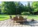 Charming backyard patio with outdoor dining set, a stone surface, and a serene view of mature trees at 132 Ragsdale Trl, Mooresville, NC 28117