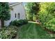 Side yard of home with well-manicured landscaping, including flowers, shrubs, and a verdant lawn at 132 Ragsdale Trl, Mooresville, NC 28117