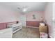 Bedroom room features pink walls, a crib, a changing table, a ceiling fan and a window at 14116 Glaswick Dr, Charlotte, NC 28278