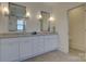 Bathroom showcasing double sinks, quartz countertops, bright mirrors and lighting, and neutral tile flooring at 1427 Main St, Charlotte, NC 28204