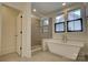 Bright bathroom featuring a luxurious soaking tub, a glass shower, and natural light from several windows at 1427 Main St, Charlotte, NC 28204
