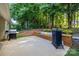 Spacious patio featuring built-in seating, a grill and a smoker, with a wooded area in the background at 1445 Deer Forest Dr, Indian Land, SC 29707