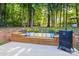 Spacious patio featuring built-in seating, a grill and a smoker, with a wooded area in the background at 1445 Deer Forest Dr, Indian Land, SC 29707