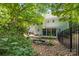 Secluded backyard featuring a stone patio, lush landscaping, and a black fence, surrounded by mature trees at 171 Highland Woods Ct, Denver, NC 28037