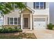 Charming home entrance with covered porch, lush landscaping, and attached garage at 2005 Amos Oaks Ln, Charlotte, NC 28215