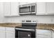Close-up of the oven and microwave with white cabinetry and granite countertops at 2005 Amos Oaks Ln, Charlotte, NC 28215