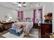 Comfortable bedroom with ceiling fan, wood floors, windows with curtains and a cozy bed at 203 Poplins Grove Church Rd, Albemarle, NC 28001