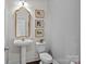 Stylish powder room features a pedestal sink, decorative mirror, and elegant wall art at 205 Church St, Mcadenville, NC 28101