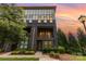 Modern townhome with brick facade, balcony, landscaped front yard, and a vibrant sunset backdrop at 2523 Irwin Stream Rd, Charlotte, NC 28208