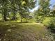 Backyard with lush green lawn, mature trees, and a shed on a hill at 370 Miracle Dr, Salisbury, NC 28146