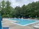 Large community pool features lounge chairs, tables with umbrellas, and lush landscaping creating a resort-like atmosphere at 3933 Cameron Creek Dr, Matthews, NC 28105