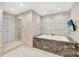 Luxurious bathroom featuring a stone wall, soaking tub, and separate glass-enclosed shower at 435 S Tryon St, Charlotte, NC 28202