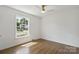 Unfurnished bedroom with wood floors, ceiling fan, and a large window overlooking green yard and neighborhood at 5817 Red Carriage Ln, Charlotte, NC 28212