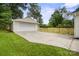 Detached garage with a large concrete driveway, complemented by lush green lawn and a charming wooden fence at 5817 Red Carriage Ln, Charlotte, NC 28212
