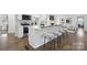 Bright and open kitchen featuring modern appliances, white cabinetry, a large island with seating, and hardwood floors at 5817 Red Carriage Ln, Charlotte, NC 28212