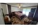 Cozy bedroom features a floral bedspread, ceiling fan, and window with sheer curtains at 5832 Thompson Rd, Charlotte, NC 28216