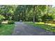 A long paved driveway leads to this house nestled among mature trees and a lush lawn at 5832 Thompson Rd, Charlotte, NC 28216