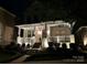 Evening view of the home's front elevation with a lighted porch and landscaped yard at 7732 Waverly Walk Ave, Charlotte, NC 28277