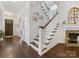 Elegant staircase with dark wood floors and white railings, adjacent to a stone fireplace at 7732 Waverly Walk Ave, Charlotte, NC 28277