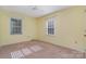 Bright bedroom with two windows, ceiling fan, neutral paint, and comfortable carpeting at 9701 Kent Village Dr, Charlotte, NC 28269