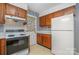 Well-lit kitchen features a classic stove, white refrigerator, and wood cabinets at 9701 Kent Village Dr, Charlotte, NC 28269