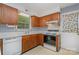 Cozy kitchen with white appliances, wood cabinets, and a view of the backyard at 9701 Kent Village Dr, Charlotte, NC 28269