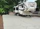 RV parked on a concrete pad with a shed nearby, surrounded by lush greenery at 104 Cardinal Dr, New London, NC 28127