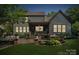 Back of house at dusk with a landscaped backyard with patio, grill, seating, and a screened in porch at 11412 Preservation Ln, Charlotte, NC 28278