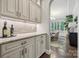 Butler's pantry featuring light gray cabinetry and stone countertops, with a view into the dining room at 11412 Preservation Ln, Charlotte, NC 28278