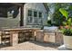 Outdoor patio with a built in kitchen with stone bar, grill, and seatting on a brick surface at 11412 Preservation Ln, Charlotte, NC 28278